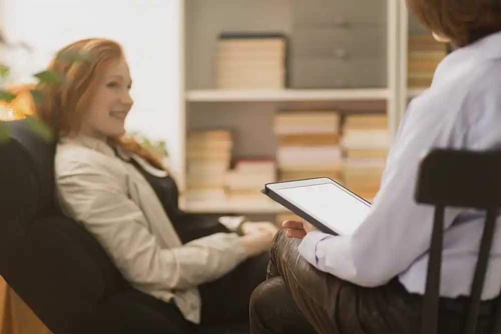 A woman sits in a counseling chair. She is getting counseling for life transitions.